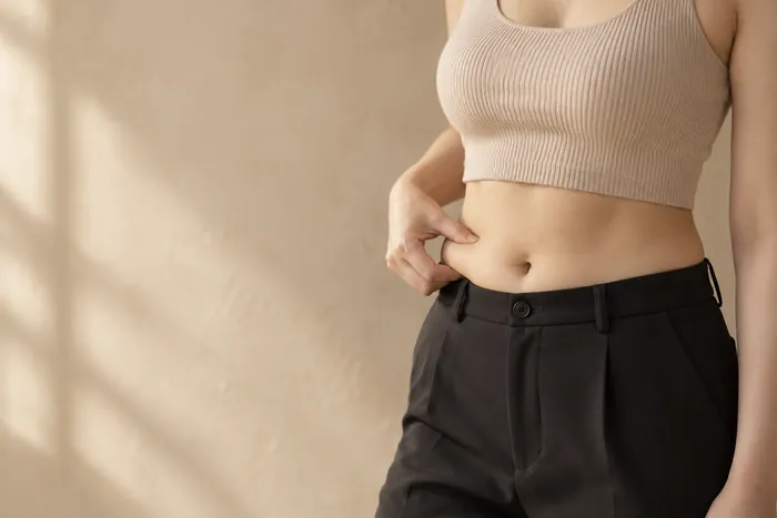 아랫배를 손으로 잡아 보는 여성