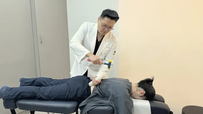 서조혁 원장이 엎드린 환자의 허리에 골타요법을 하는 모습