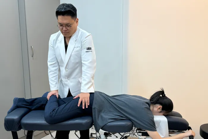서조혁 원장이 엎드린 환자의 허리와 골반을 추나요법으로 교정하는 모습