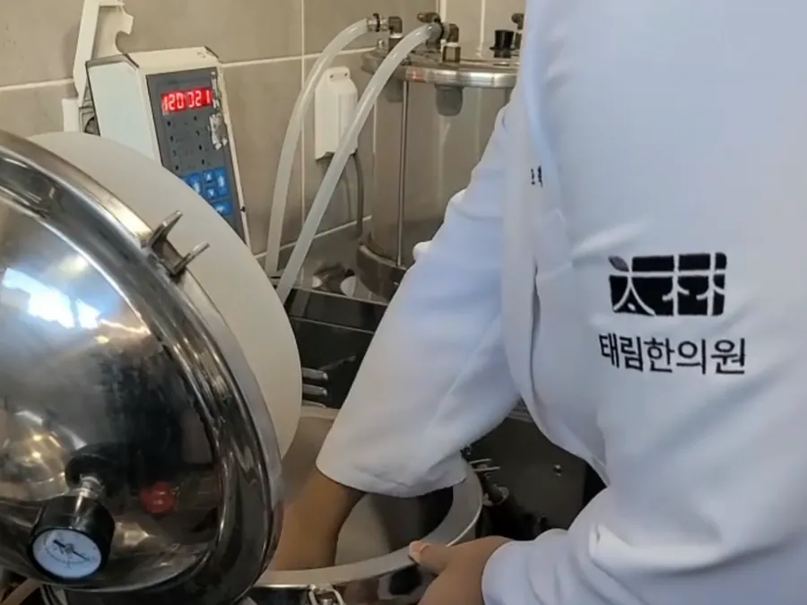 태림한의원 한약 추출 시설에서 가운 입은 원장이 한약을 달이는 모습